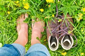 bare feet standing in grass next to shoes